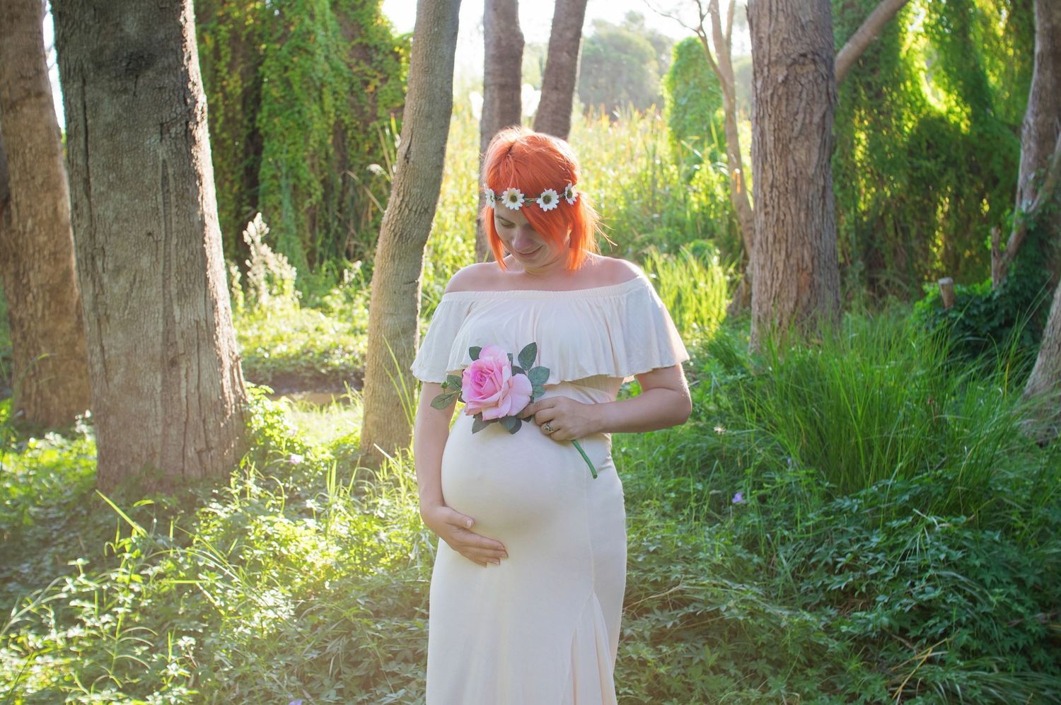 woman smiling at her pregnant belly outdoor