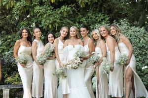 Cora Emilie Media Bridesmaids wearing elegant white dresses pose together outdoors with matching bouquets.