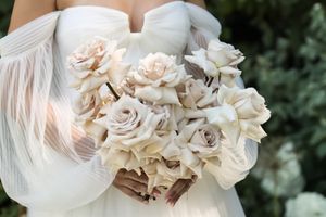 Cora Emilie Media Delicate white roses and flowers arranged in an elegant wedding bouquet.