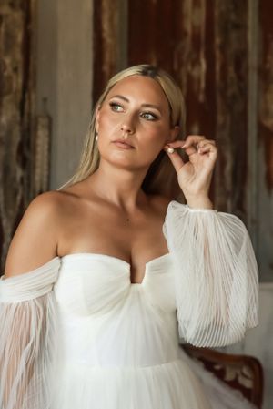 Cora Emilie Media A bridal portrait showcasing an off-shoulder wedding gown with flowing sleeves.