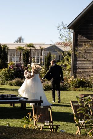 Cora Emilie Media Elegant outdoor wedding venue with wooden benches and natural garden setting.