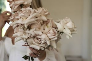 Cora Emilie Media A delicate bouquet of pale pink roses tied with ribbon.