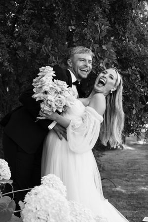 Cora Emilie Media Black and white wedding photos showing a couple embracing outdoors with a beautiful white floral bouquet.