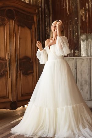 Cora Emilie Media A wedding dress with puffy sleeves and full tulle skirt in a vintage-style room.