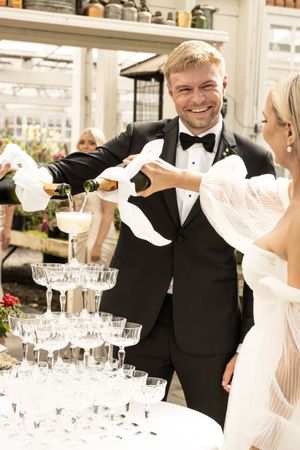 Cora Emilie Media Wedding celebration with champagne tower being poured in elegant indoor setting.