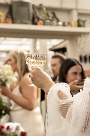 Cora Emilie Media Guests raise champagne glasses in celebration at an indoor wedding reception.