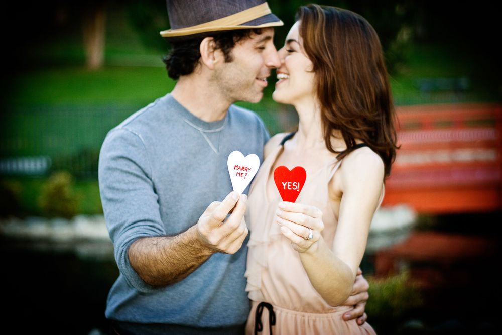 Romantic couple sharing a moment with heart-shaped valentines in a park.