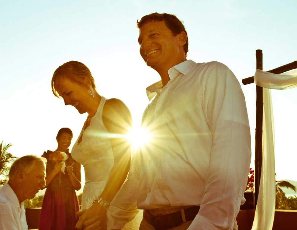 Outdoor ceremony scene with sunburst through white-clad figures.