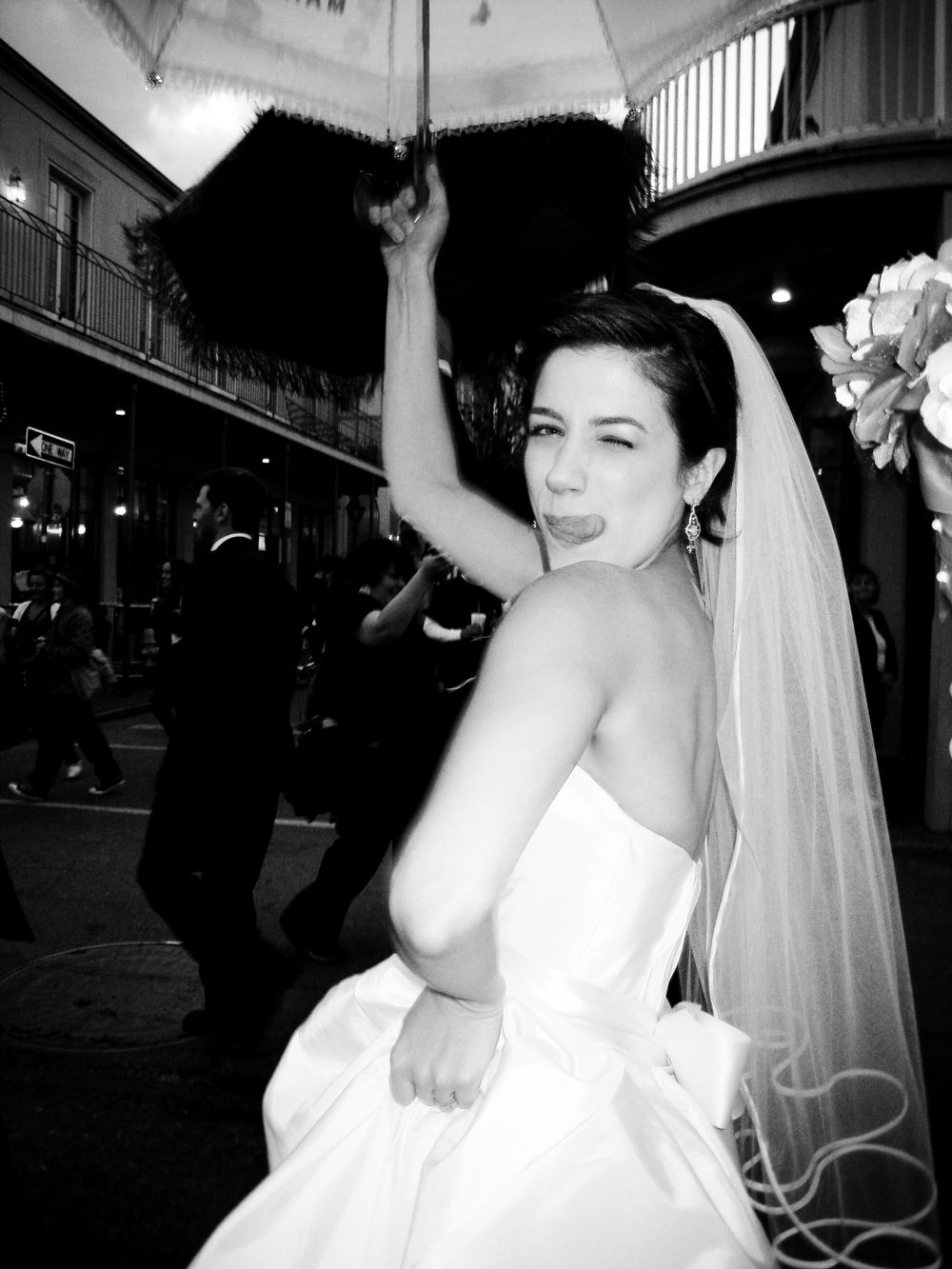 Bride with parasol celebrating on a street in black and white.