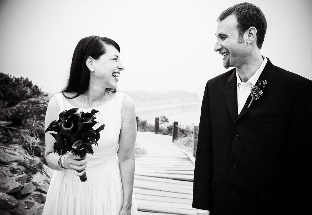 Wedding couple sharing joyful moment on wooden boardwalk.