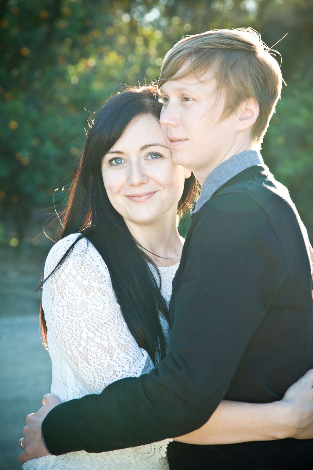 Couple embracing outdoors in sunlit natural setting with romantic atmosphere.