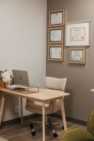 Professional office desk setup with framed certificates and modern furniture.