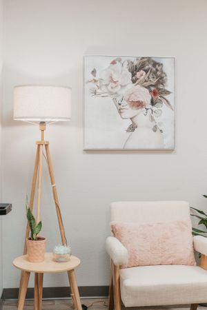 Modern reading nook with tripod lamp, floral artwork and pink accents.