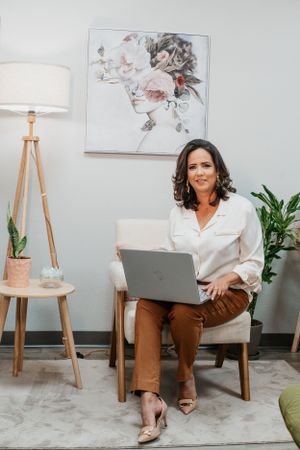 Professional working on laptop in stylish office space with modern art and lighting.