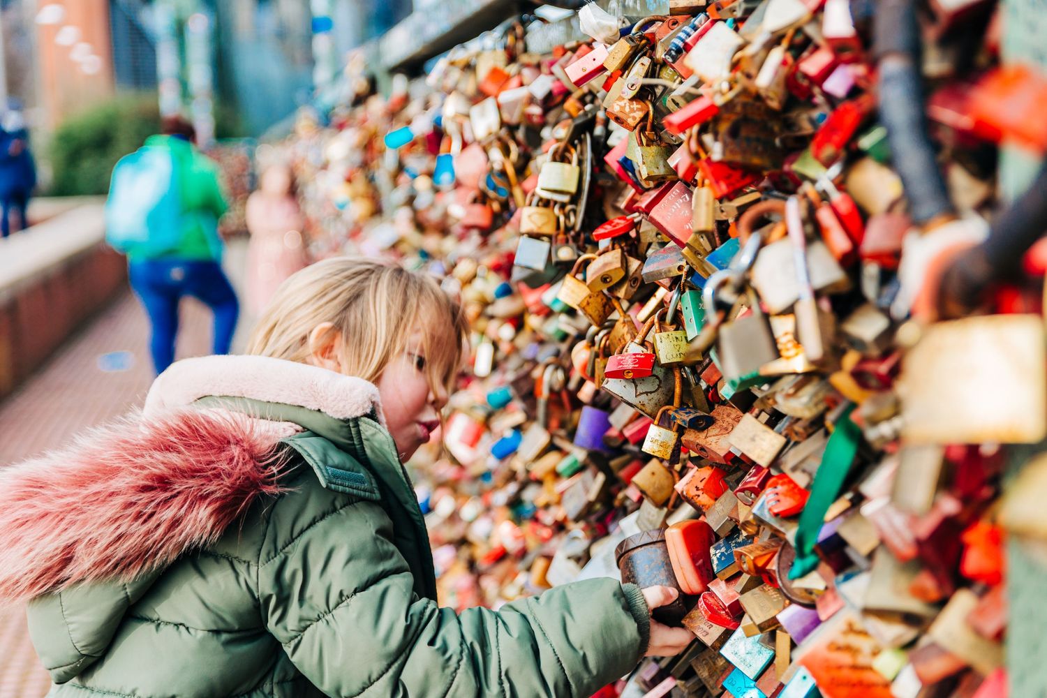 Love locks displayed on metal railings with colorful padlocks of various sizes.