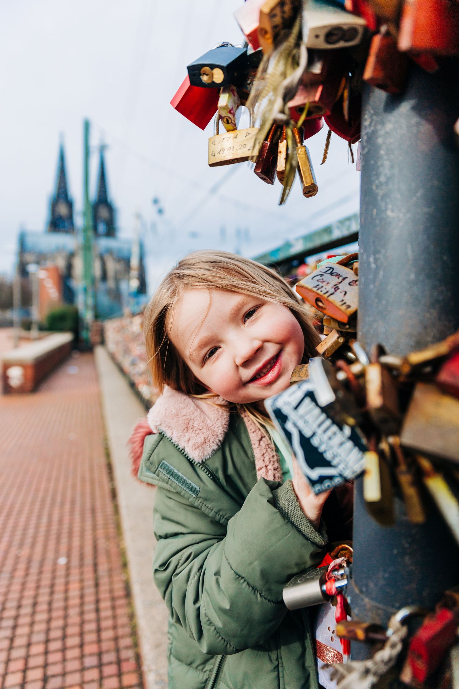 A joyful winter moment at the Cologne love locks bridge with cathedral spires in background.