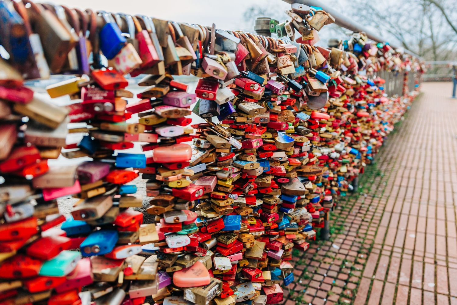 Colorful love locks densely attached to bridge railing creating a romantic wall of memories.