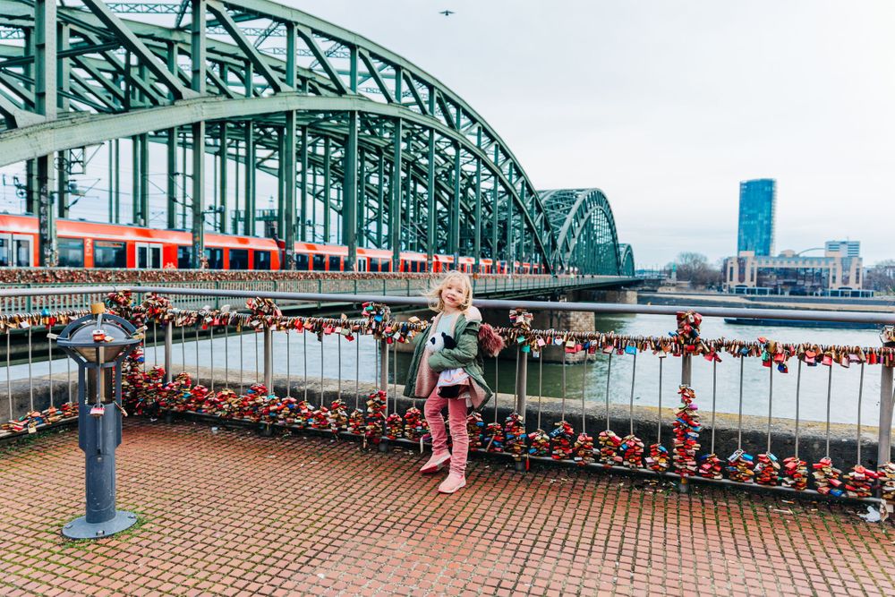 View of the Hohenzollern Bridge in Cologne with love locks and train crossing.