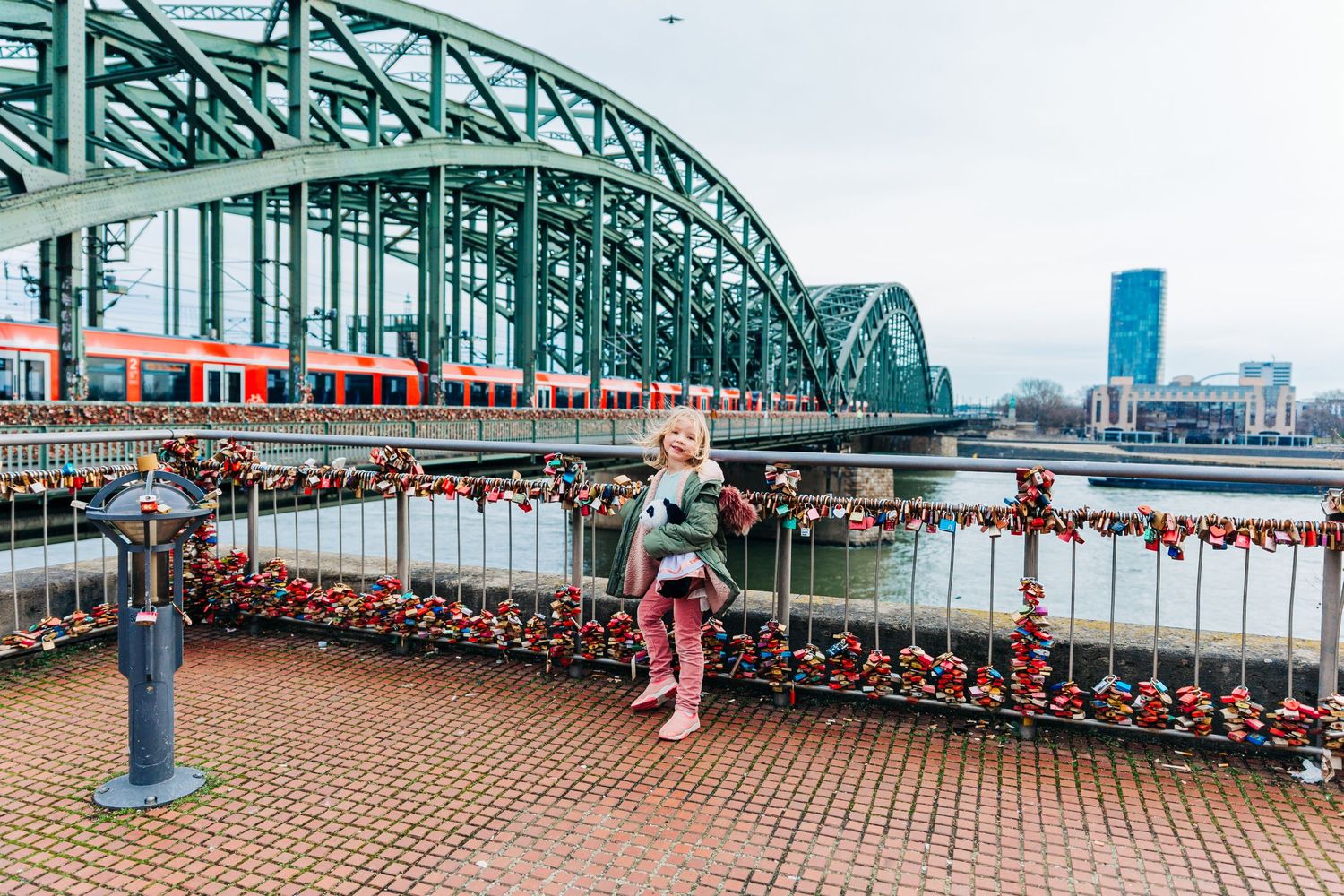 View of the Hohenzollern Bridge in Cologne with love locks and train crossing.
