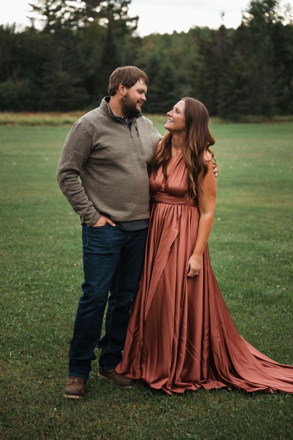 Couple glancing at each other in field in Orr, Minnesota.