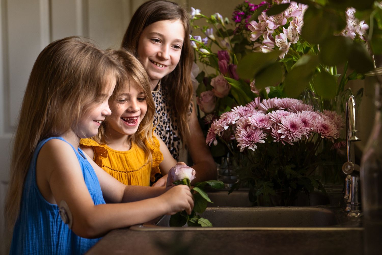 three sisters surrounded by flowers in home photography session at Ft Sam Houston in San Antonio Texas