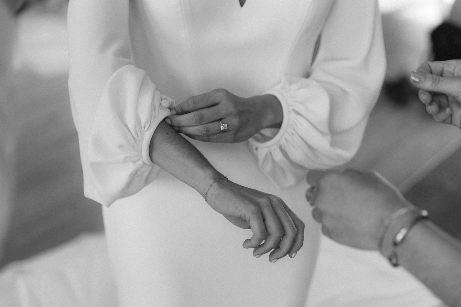 Close-up details of hands in white attire during an elegant wedding ceremony.