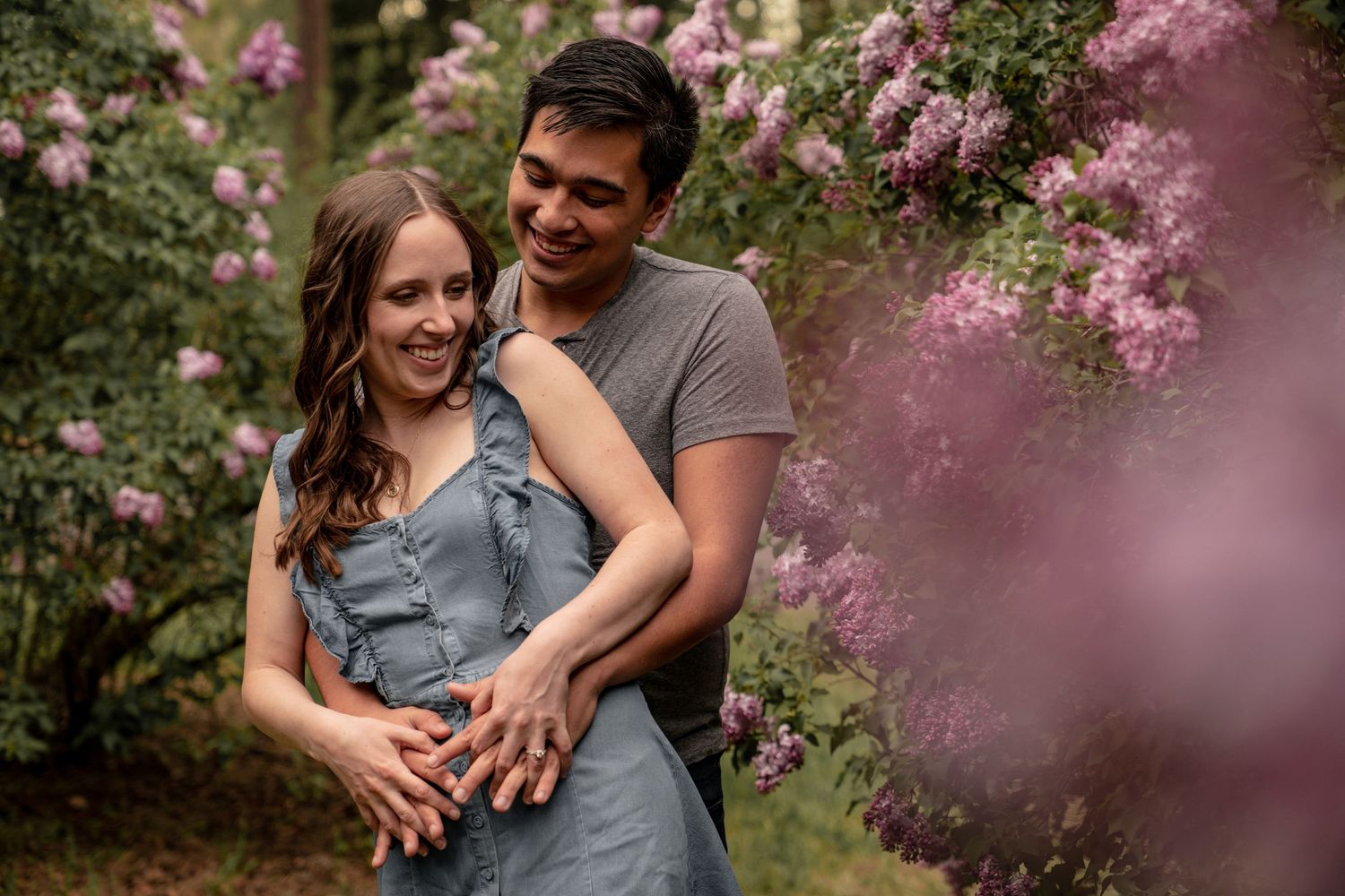 A romantic moment captured in a garden surrounded by blooming pink flowers.