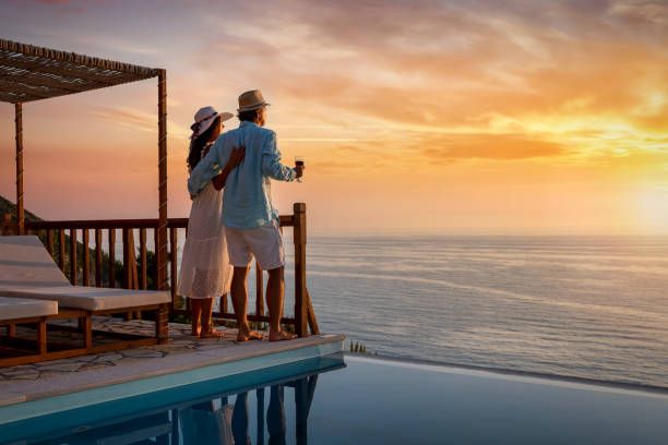 Couple enjoying sunset views from an oceanfront deck with infinity pool.
