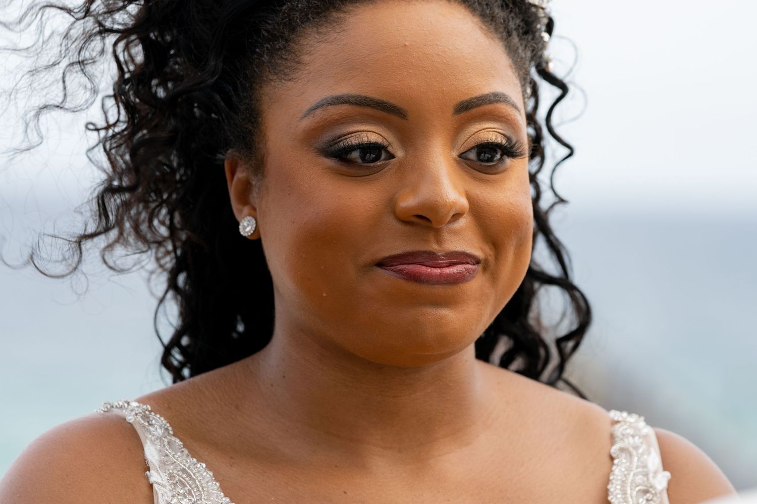 Portrait featuring elegant lace dress detail and natural curly hairstyle.