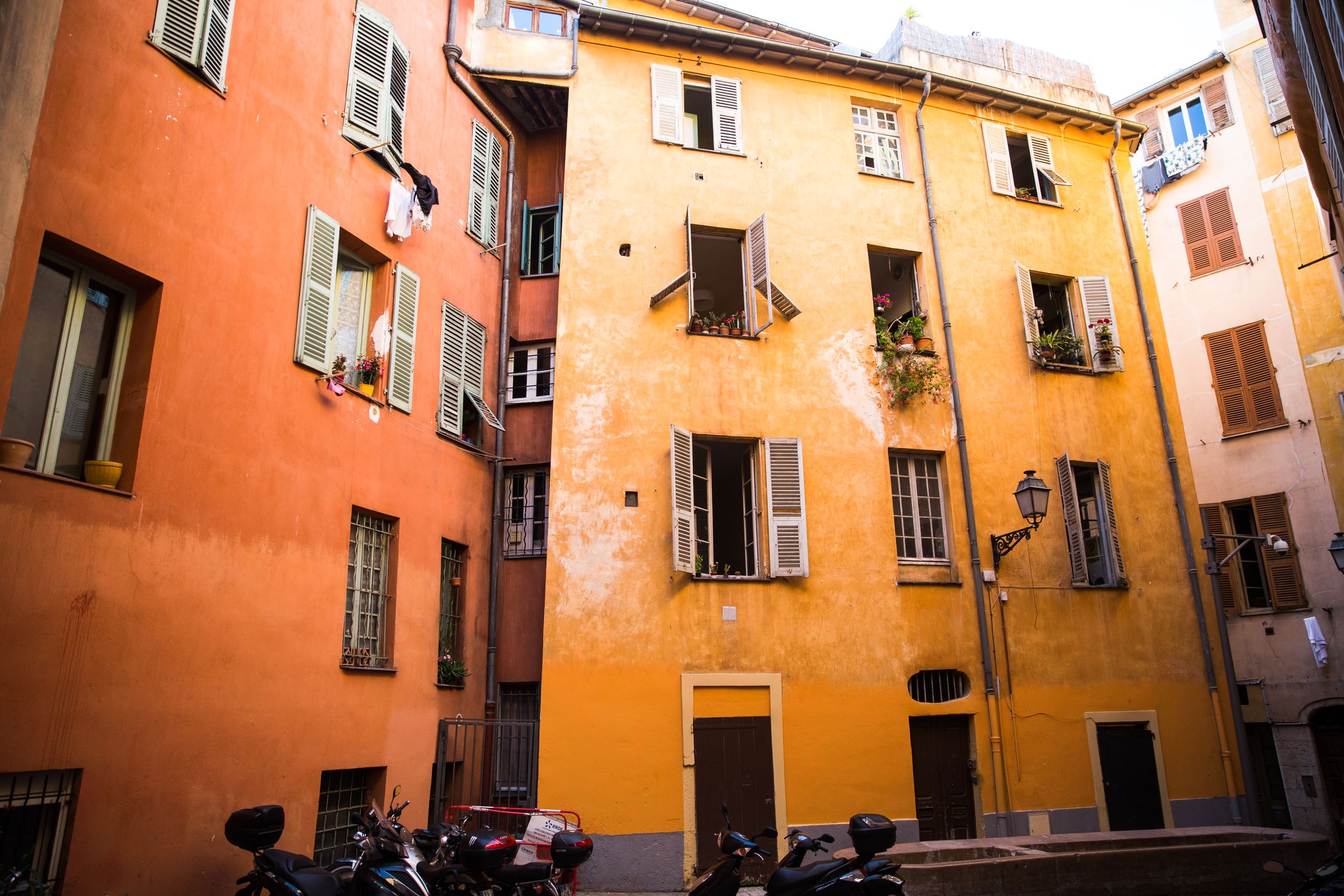Colorful orange and yellow buildings line a narrow European alley with traditional architecture and balconies.