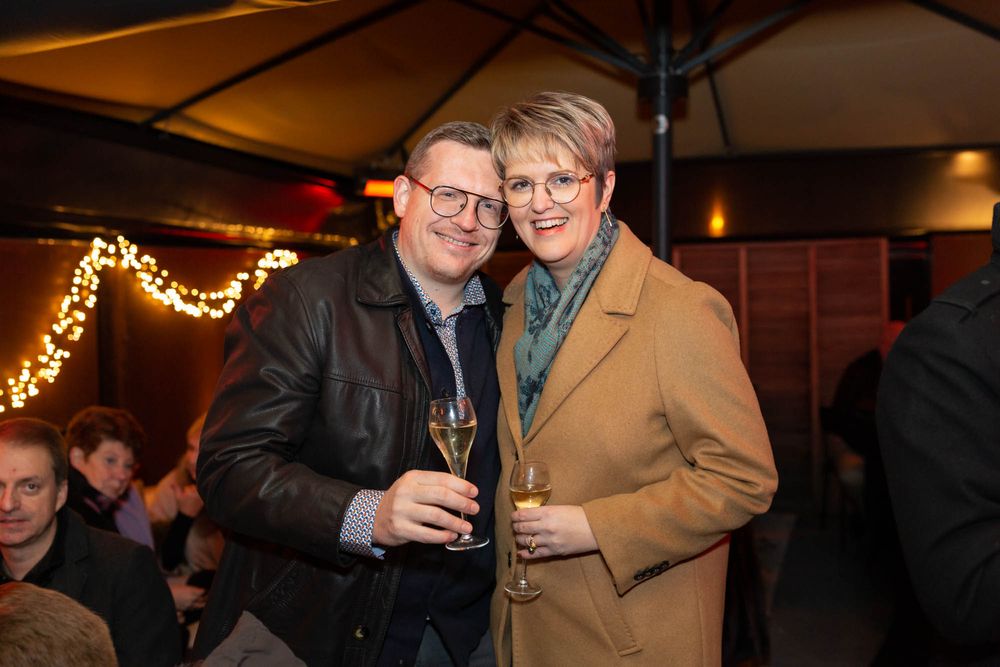 A couple celebrates with champagne at an evening party under warm lighting.