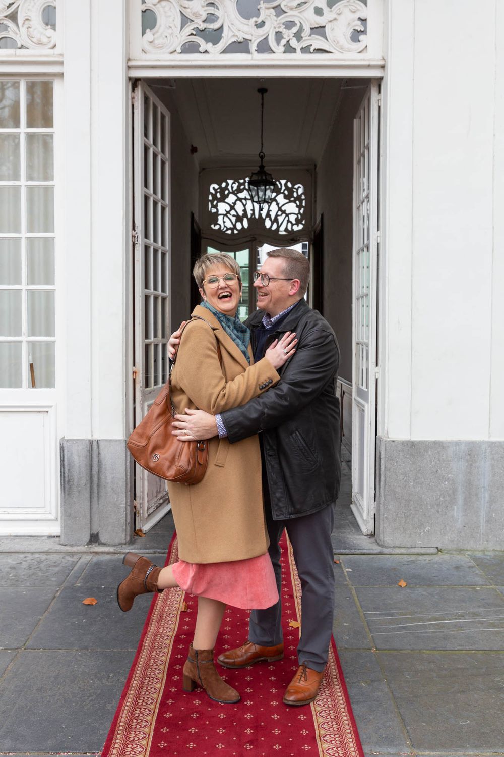A joyful couple embracing in a doorway with decorative architectural details.