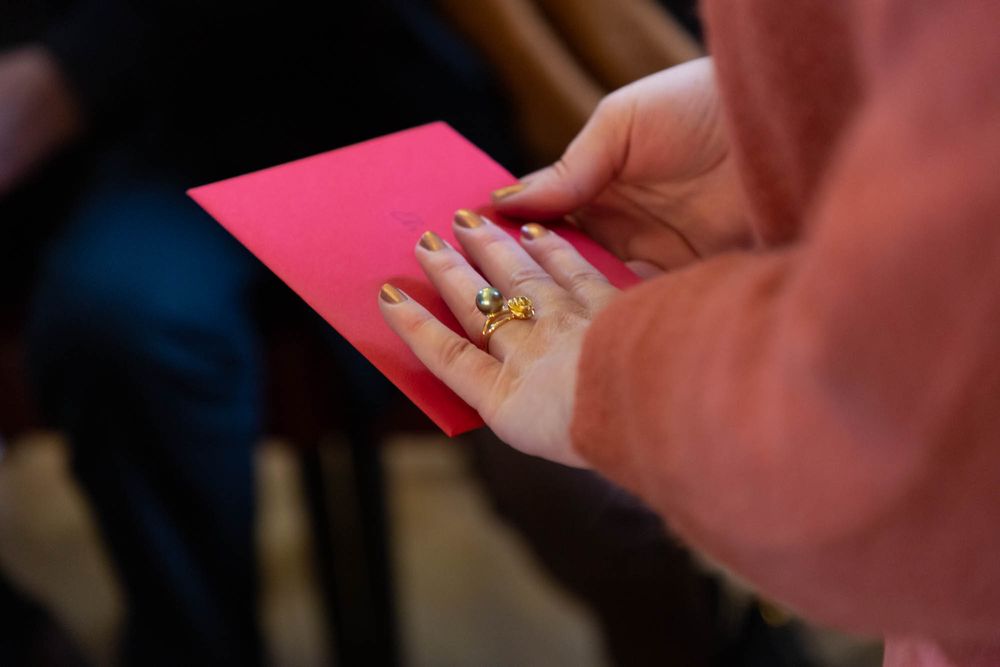 Close-up of hands holding a bright pink card during an event.