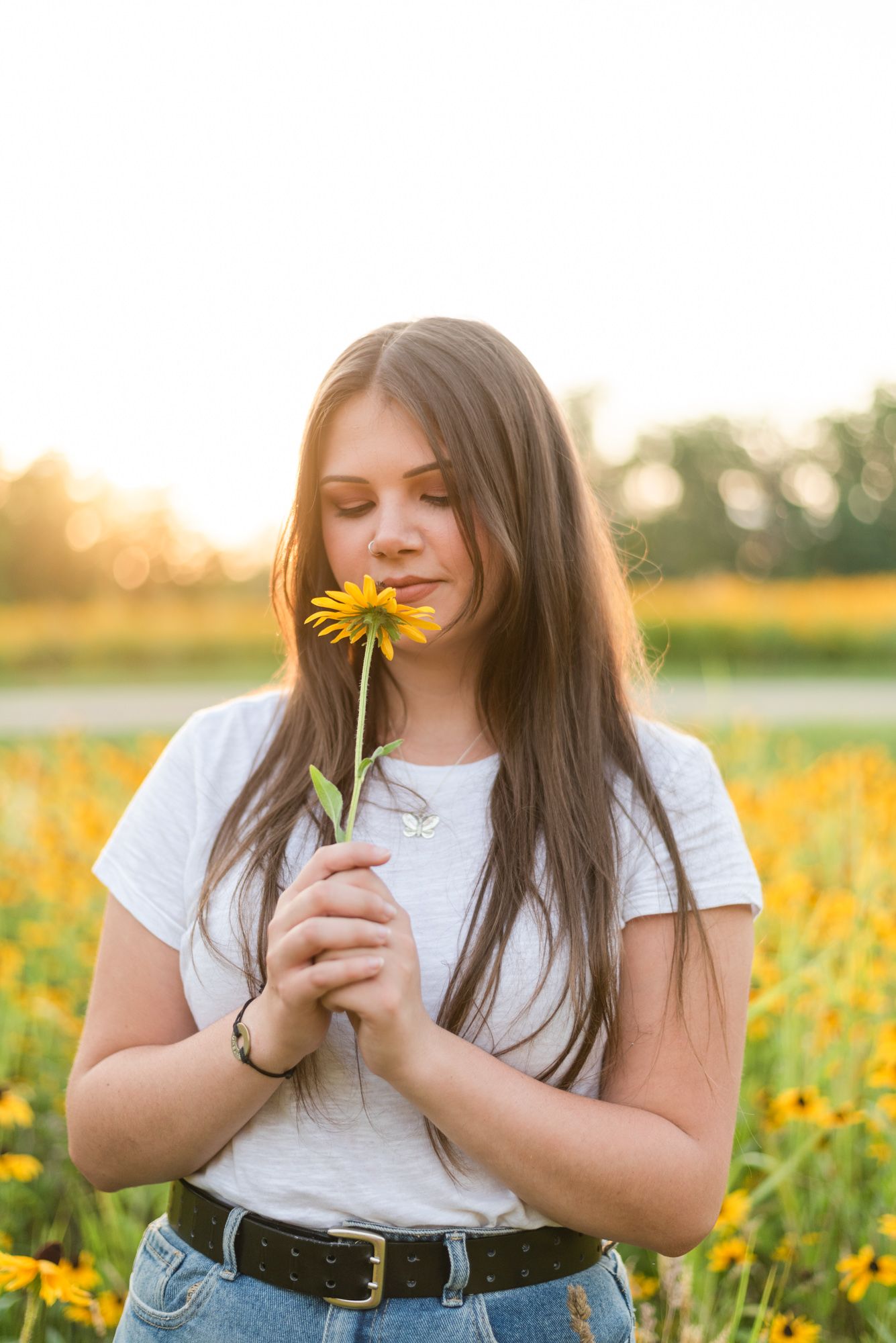 Girl smelling flower in meadow in golden sunlight at Hartwood Acres in Pittsburgh Pennsylvania