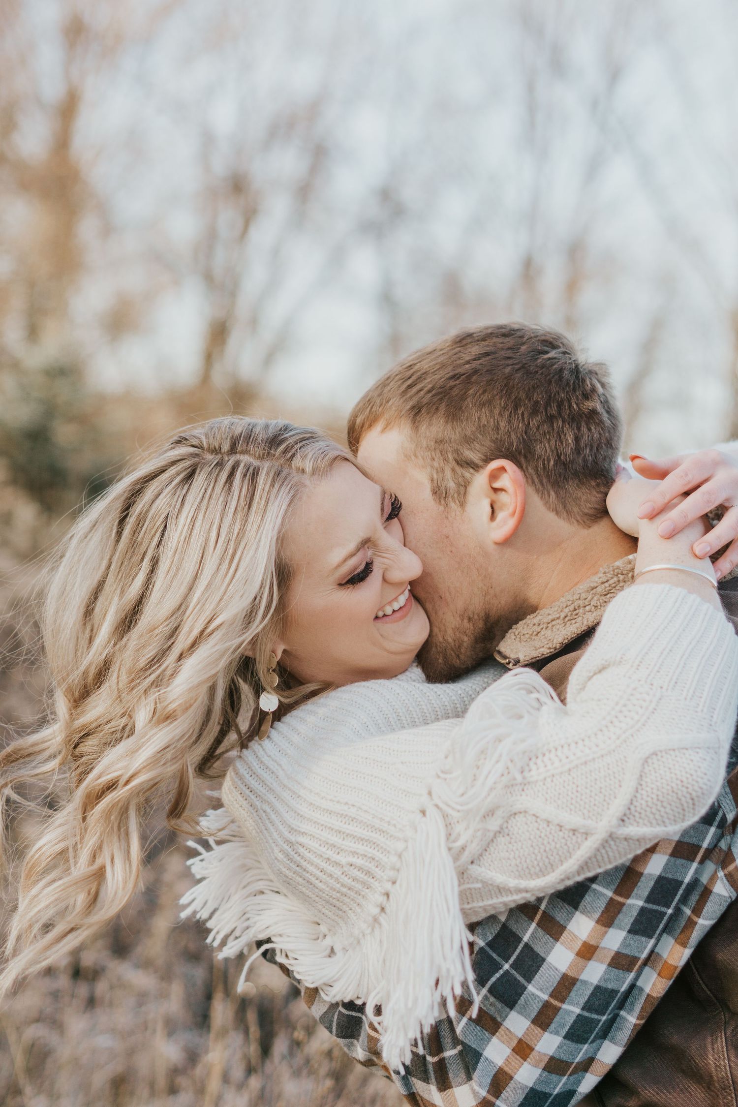 Intimate winter couple photos with woman in white scarf against natural backdrop.