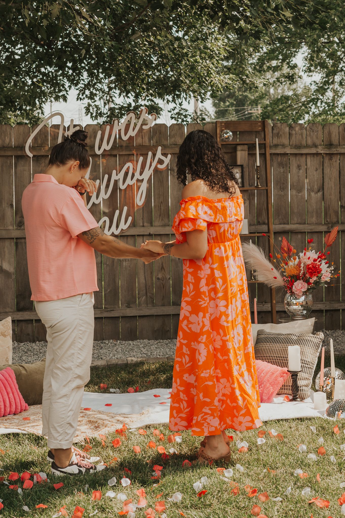 Backyard celebration scene with orange floral dress and pink decorations.
