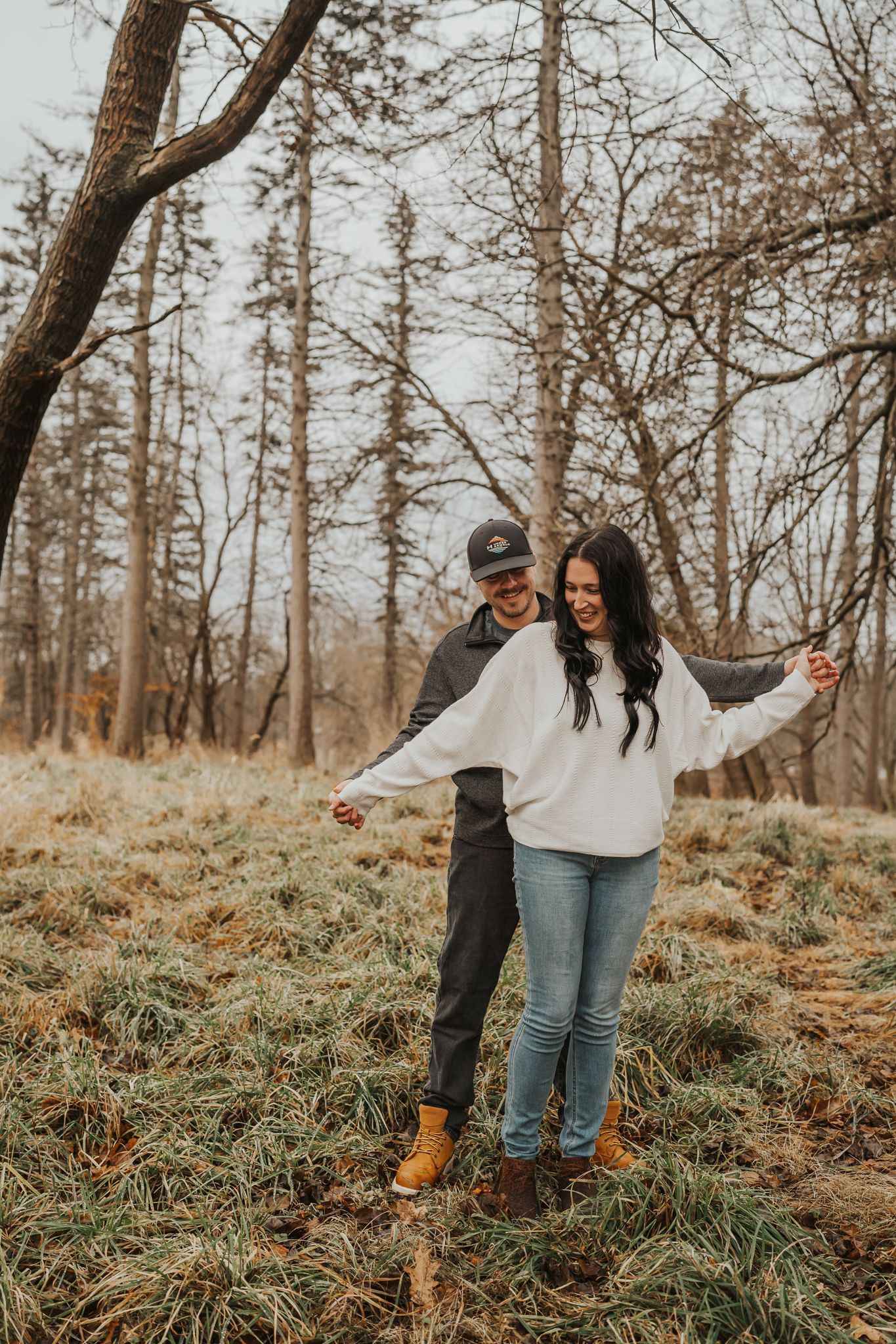 Couple enjoying an autumn walk together in a wooded area wearing casual sweaters and boots.