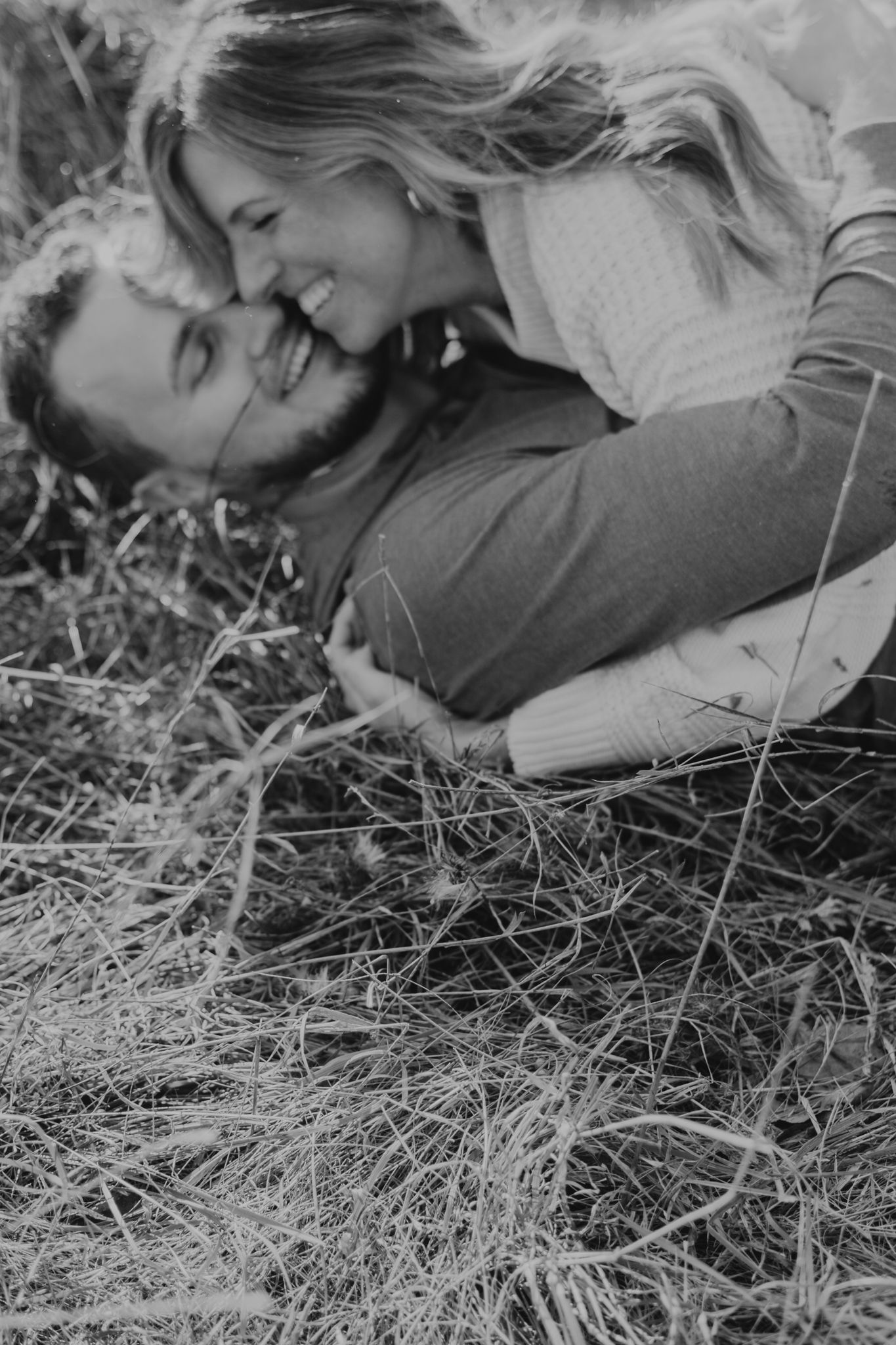 Close-up black and white shot of someone laying in dried grass.