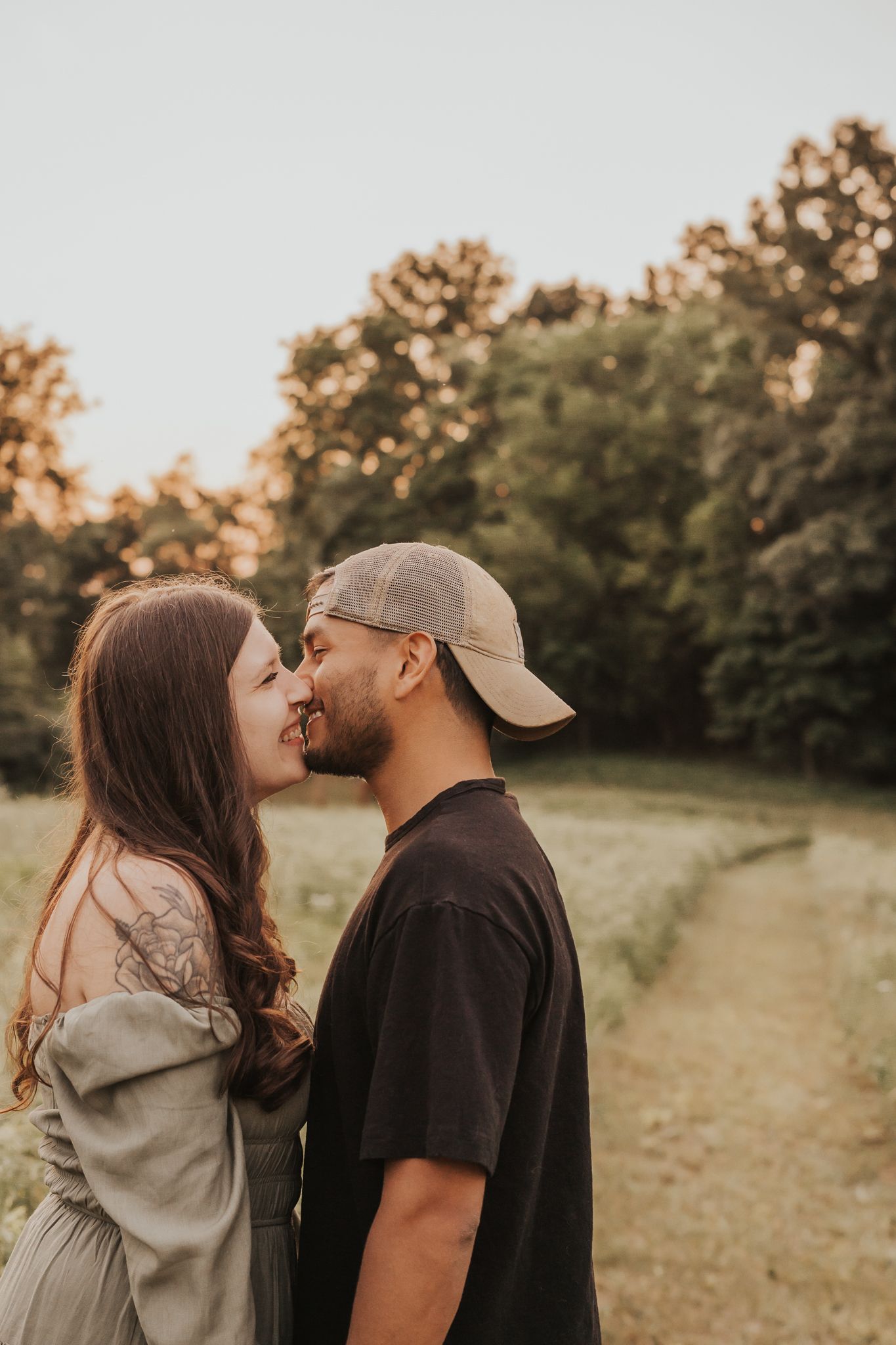 Michigan couple sharing affectionate kisses in outdoor setting during sunset.