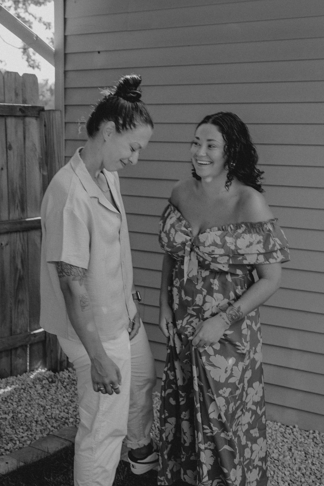Two people sharing a joyful moment together against a grey house exterior.