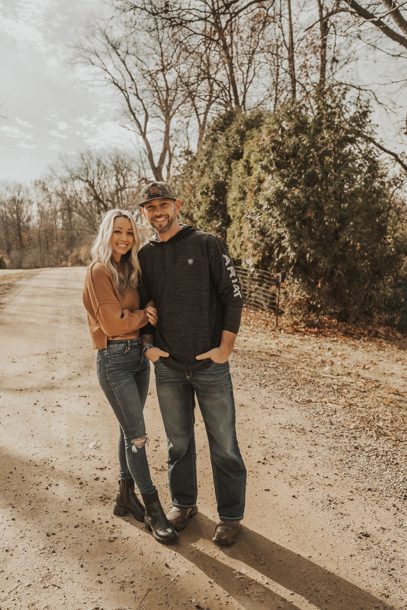 Couple in casual denim and sweaters standing together on a sunny autumn path in Parma Michigan.