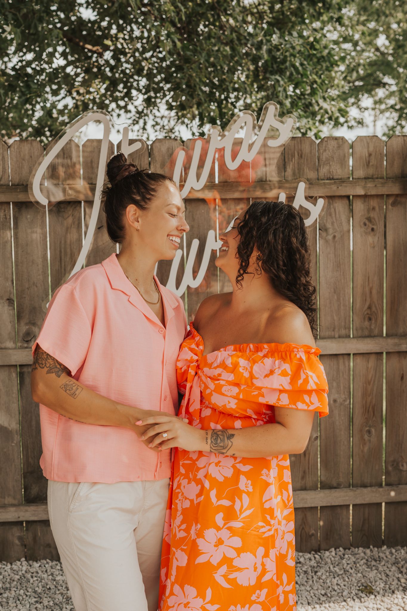 Two people embracing at an outdoor celebration with orange and pink attire.