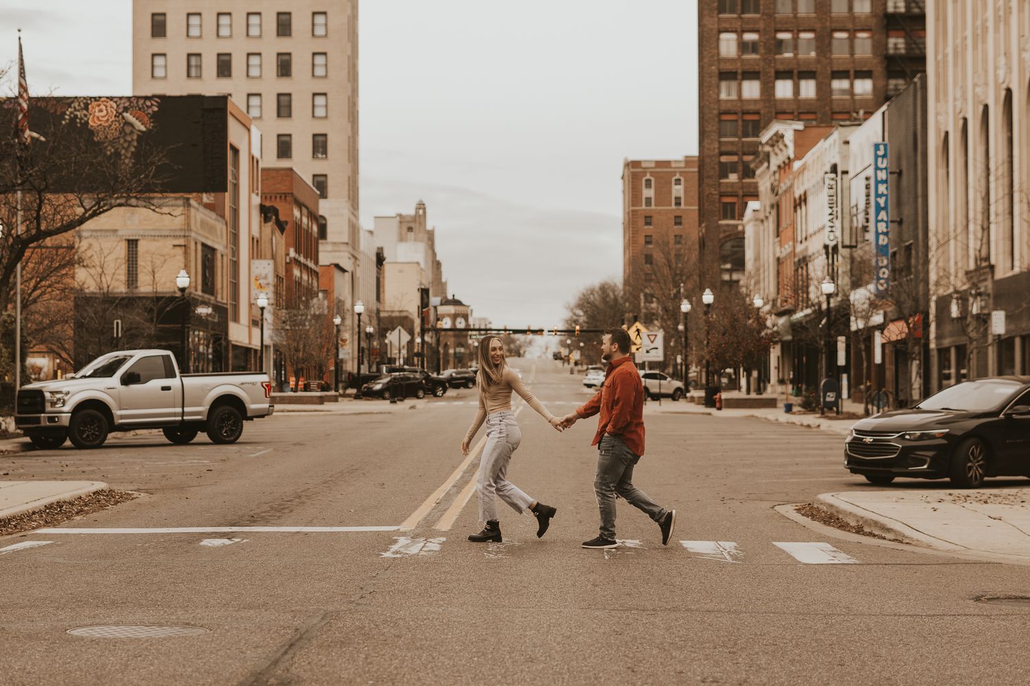 Urban Michigan engagement photo sequence showing couple walking and dancing in city streets.