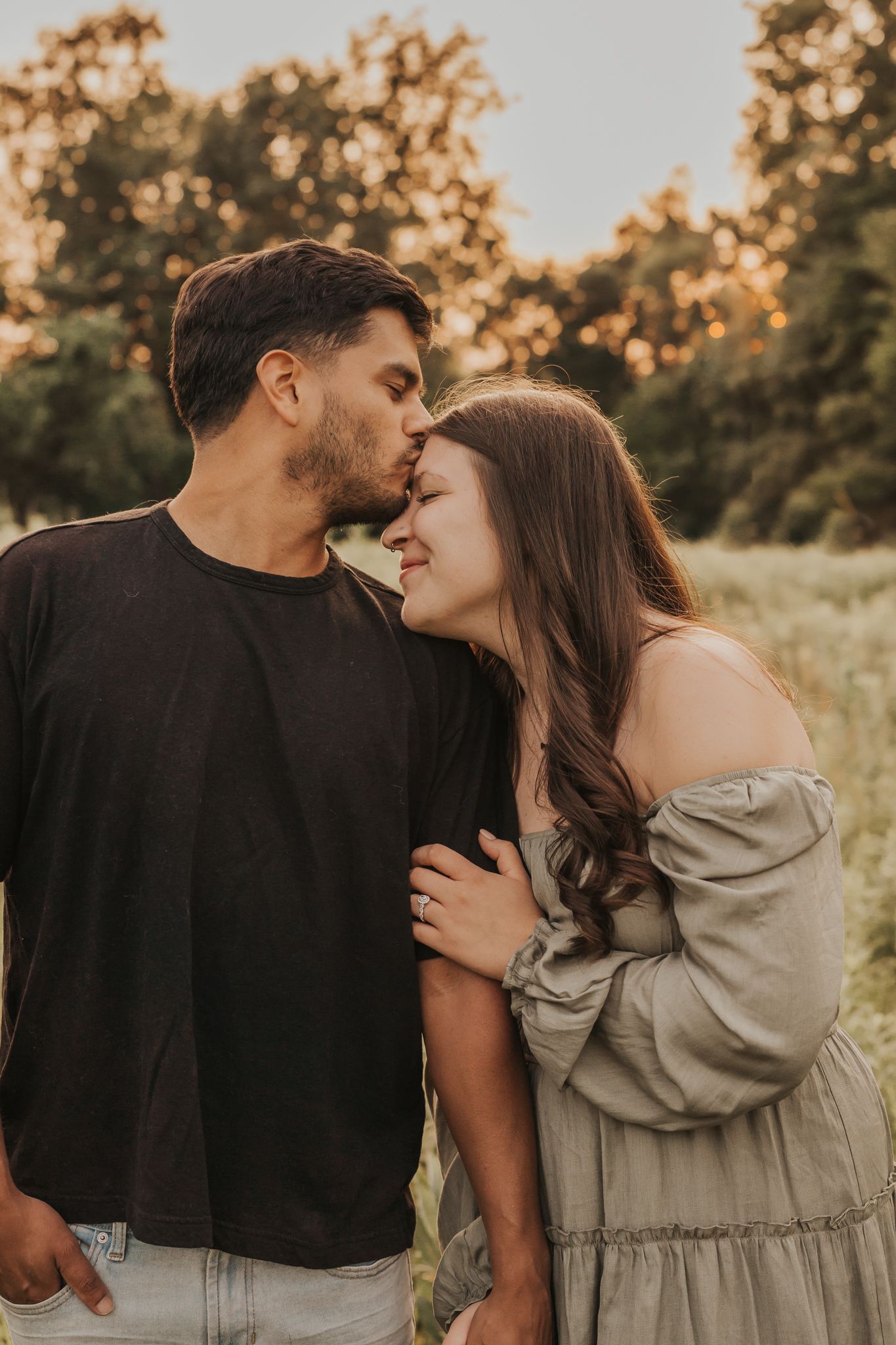 Intimate couple sharing tender moments during golden hour in natural setting.