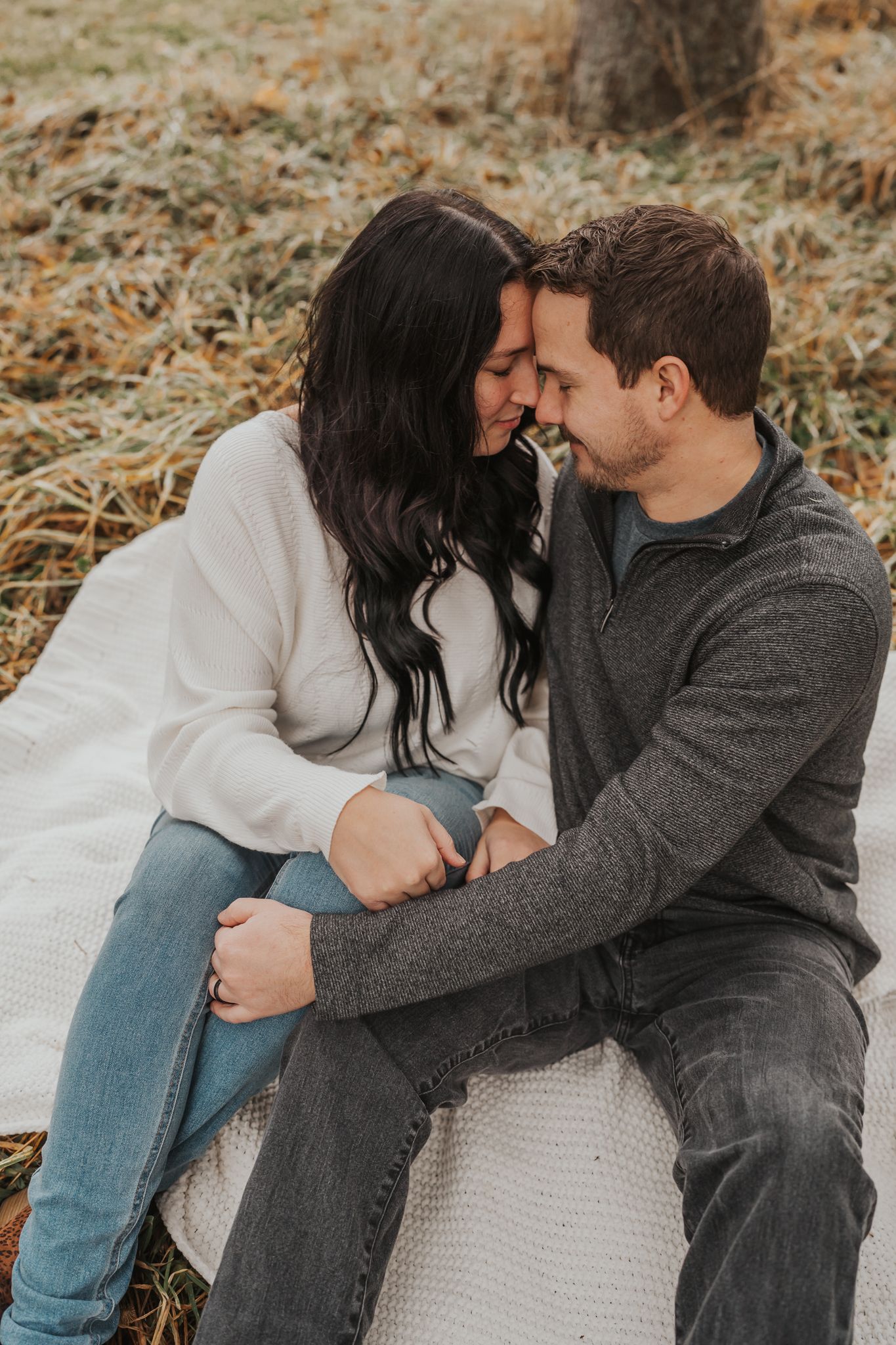 Couple in casual wear sharing tender moment outdoors in fall scenery.