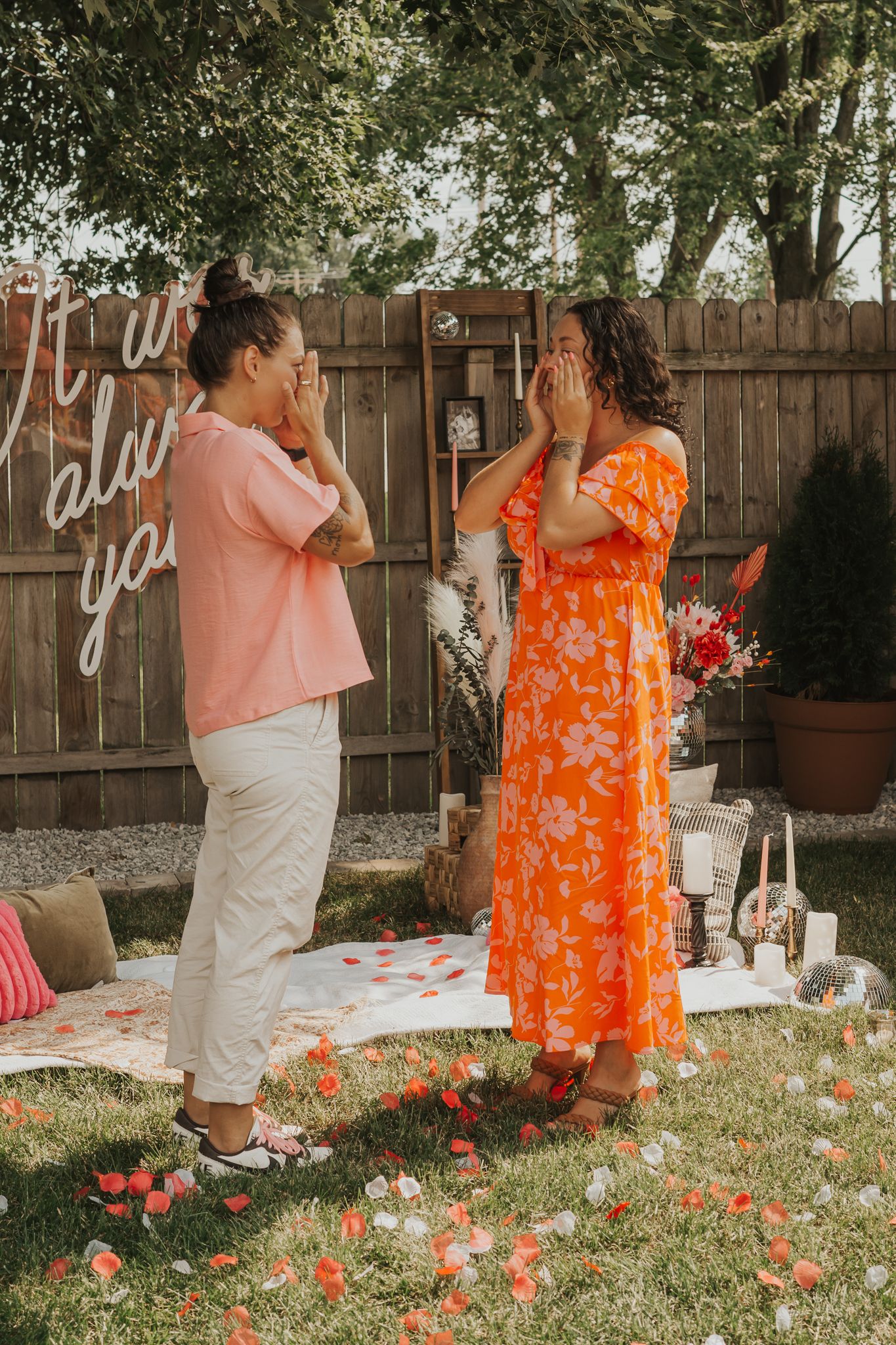 Two people celebrating their engagement in a Jackson MI backyard with floral decorations and string lights.