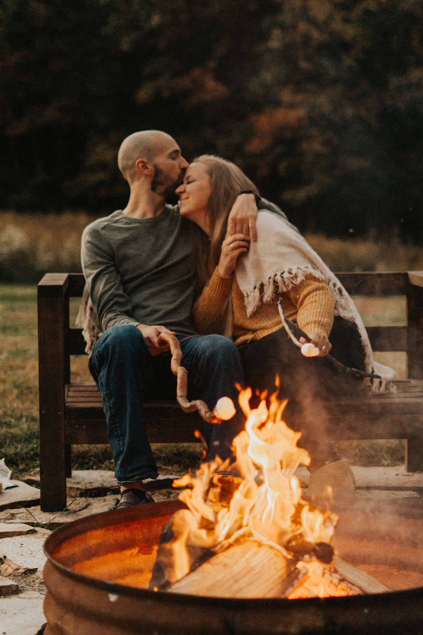 Couple relaxing by warm bonfire on autumn evening.
