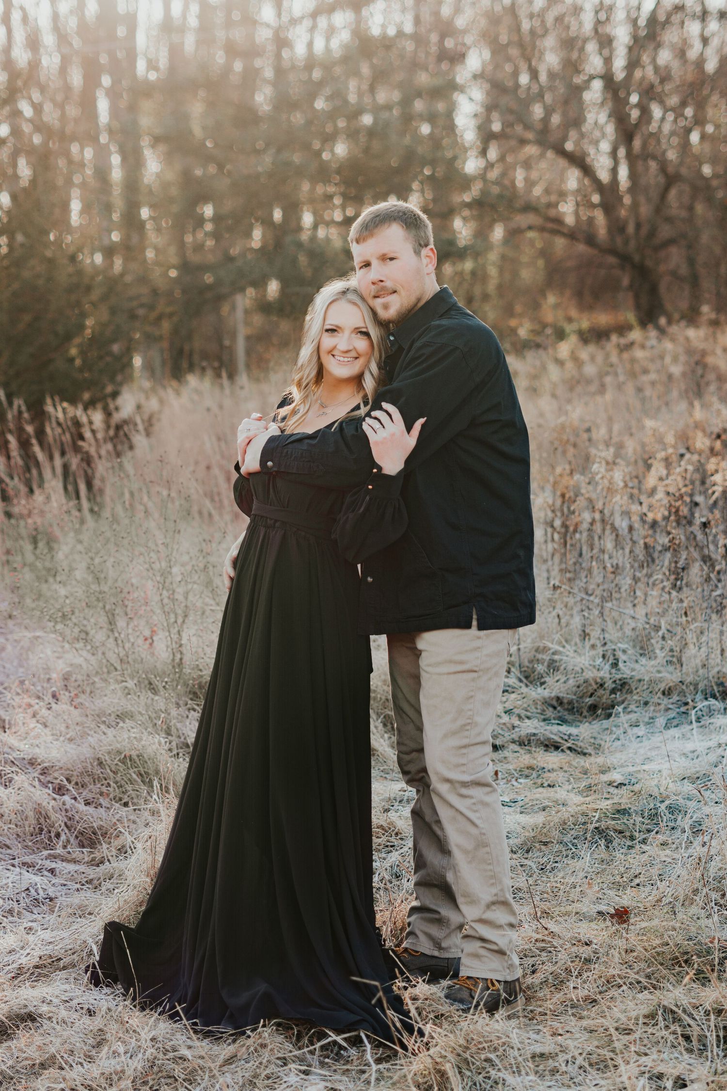Winter engagement photos of couple in natural field setting with dried grass.