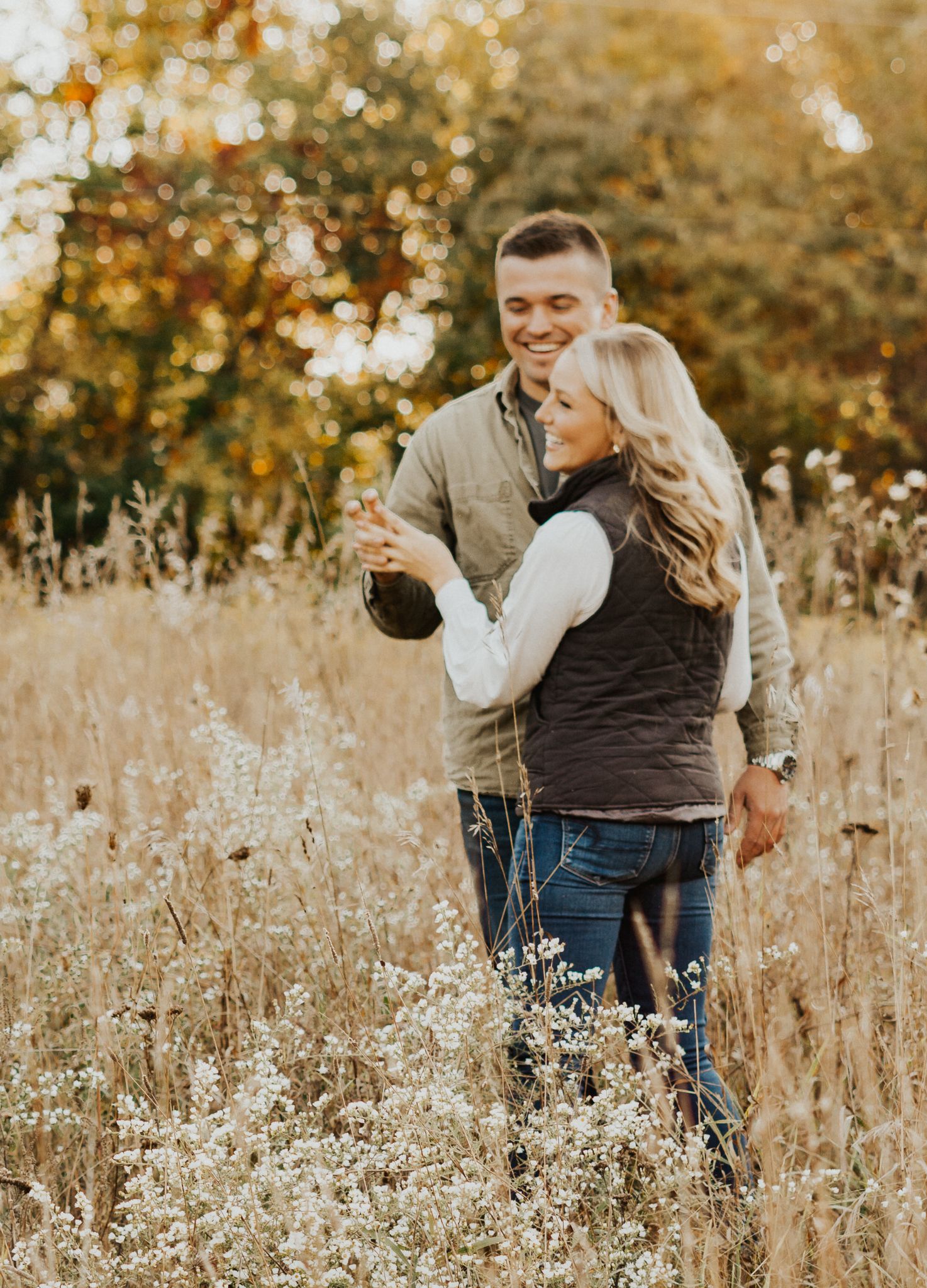 An Indiana couple embraces in a golden autumn field with tall grass and warm sunlight.