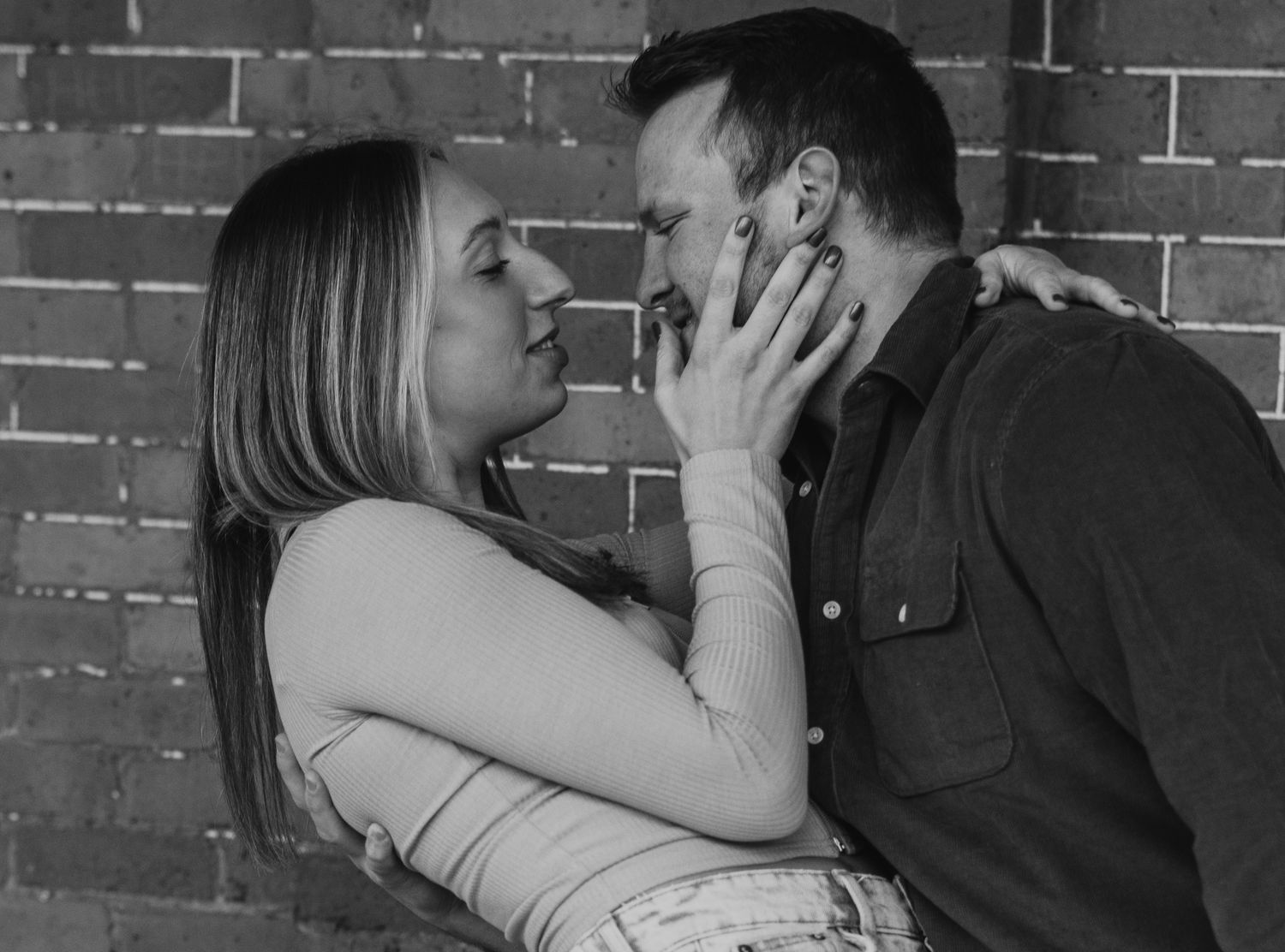 Black and white photo series of intimate couple moments against brick wall.